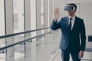 Excited office worker dressed in formal clothes managing business project through virtual reality photo