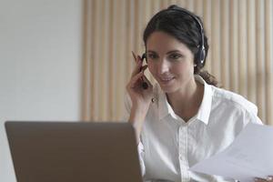 joven italiana agente del centro de llamadas en auriculares hablando con el cliente, consultando al cliente en línea foto