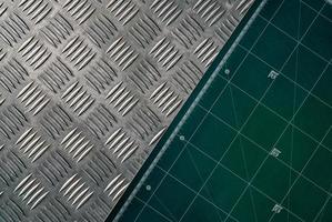 Industrial metal checker plate and green cutting mat. Metal checker plate texture background. Metal checkerplate for anti skid. Embossed metal sheet floor. Silver bump ground with art pattern. photo