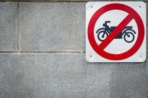 Motorcycle no entry sign install on concrete wall in front of tunnel under road. Traffic sign to prohibit motorcycle. Restrictive signs. Motorcycle caution and stop driving to this way. Ban motorbike photo