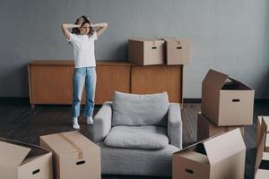 European woman has headache from moving alone. Young lady is exhausted with boxes unloading. photo