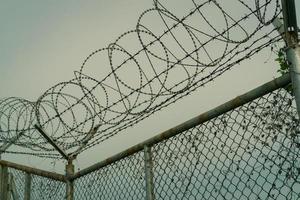 Prison security fence. Barbed wire security fence. Razor wire jail fence. Barrier border. Boundary security wall. Prison for arrest criminals or terrorists. Private area. Military zone concept. photo