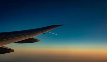 ala de avión sobre la ciudad. avión volando en el cielo azul. vista panorámica desde la ventana del avión. vuelo de aerolínea comercial por la mañana con luz solar. ala de avión por encima de las nubes. concepto de mecánica de vuelo. foto