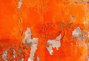 Orange color painted on concrete wall are peeling. Old and dirty wall texture background with space. photo