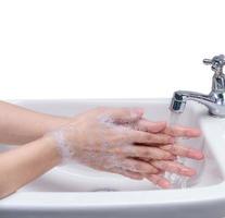 Woman washing hand with soap foam and tap water in bathroom. Hand clean under faucet on sink for personal hygiene to prevent flu and coronavirus. Good procedure of hand wash to kill bacteria, virus. photo