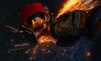 Industrial worker using angle grinder cutting metal. Worker working with angle grinder and has orange sparks. Tool for cut and grinding steel. Safety in industrial workplace. Metal factory industry. photo
