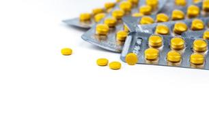 Yellow tablets pills and blister pack. Pharmacy drugstore background. Pharmaceutical industry. Pharmaceutics concept. Selective focus on small yellow tablets pills. Healthcare and medicine concept. photo