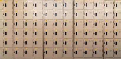 Closeup beige locker with lock and numbered yellow tags at locker room. Locker for safety and security storage. Row of locker with locked door background. photo