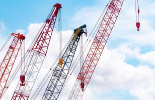 Crawler crane against blue sky and white clouds. Real estate industry. Red crawler crane use reel lift up equipment in construction site. Crane for rent. Crane dealership for construction business. photo