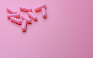 Pink capsule pills on pink background. Woman health insurance budget. Pharmacy store banner. Pharmaceutical industry. Vitamins and supplements. Capsule pills industry. Happy pills. Pills of love. photo