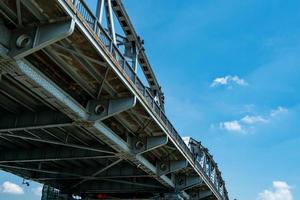 estructura de puente de acero contra el cielo azul y las nubes blancas. construcción de ingeniería de puentes de hierro. puente de metal fuerte y resistente. arquitectura de puentes de carretera. infraestructura. foto
