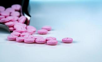 Pink tablets pills on blurred background of drug tray. Pharmaceutical industry. Pharmacy products. Vitamins and supplements. Medication use in hospital or drugstore. Global drug retail market. photo