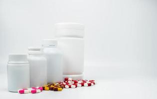 Cápsulas de antibióticos y botella de plástico con etiqueta en blanco aislado sobre fondo blanco con espacio de copia. concepto de resistencia a los medicamentos. uso de medicamentos antibióticos con un concepto de atención médica razonable y global. foto