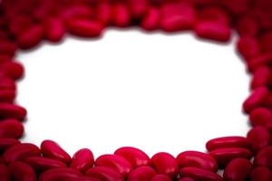 Selective focus of red kidney shape sugar coated tablet pills on white background with copy space photo