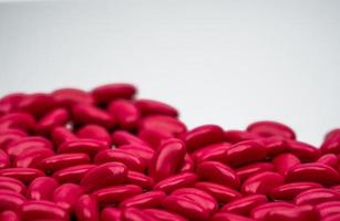 Selective focus of red kidney shape sugar coated tablet pills on white background with copy space photo