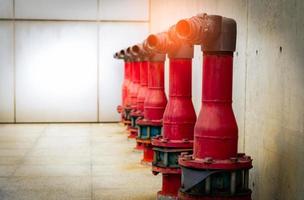 Fire safety pump on cement floor of concrete building. Deluge system of firefighting system. Plumbing fire protection. Red fire pump in front of concrete wall. High pressure fire safety pump. photo