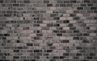 Dark brick wall texture background. Old vintage pattern wallpaper. Grunge brick wall interior building architecture. Rough brick wall texture. Loft style home interior design. Black and gray wall photo