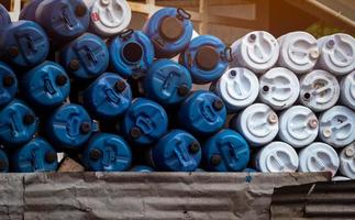 Selective focus on empty old chemical barrels. Blue and white oil drum. Plastic oil tank. Toxic waste warehouse. Hazard chemical barrel. Industrial waste plastic drum. Empty can and QC pass label. photo