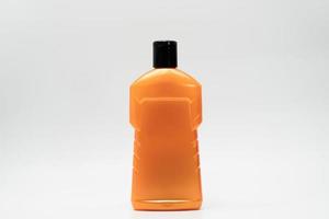 Orange color cosmetic bottle with black cap isolated on white background with copy space and blank label. Dandruff shampoo bottle with modern design. Personal hair and body care product in bathroom.