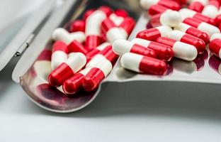Red-white antibiotic capsule pills on stainless steel drug tray. Antibiotc drug resistance. Prescription drugs. Pharmaceutical industry. photo
