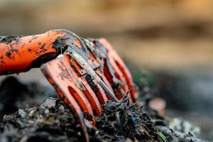 rastrillo naranja de primer plano sobre un montón de residuos plásticos sucios sobre un fondo borroso. el concepto de contaminación ambiental de la playa limpia la basura en la playa. basura del océano. costa contaminada. foto