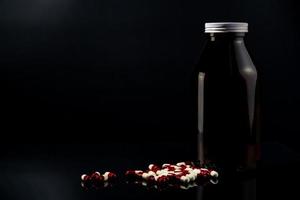 píldoras de cápsulas antimicrobianas rojas y blancas y botella de vidrio ámbar sobre fondo oscuro con etiqueta en blanco y espacio de copia para texto. resistencia a los antibióticos y uso de medicamentos con un concepto razonable. foto