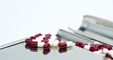 Red-white antibiotic capsule pills on stainless steel drug tray. Prescription drugs. Antibiotic drug resistance. Pharmaceutical industry. photo