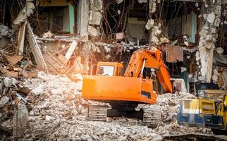 destruido edificio industrial. Demolición de edificios por explosión. edificio de hormigón abandonado con escombros y chatarra. ruina del terremoto. edificio dañado o derrumbado por el desastre del huracán. retroexcavadora foto