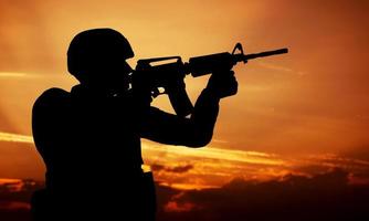 Soldier shooting with his weapon, rifle at sunset. War photo