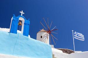 ciudad de oia en la isla de santorini, grecia. molinos de viento famosos, iglesia, bandera. foto