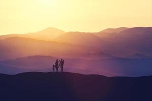 Family with two children standing on a hill photo