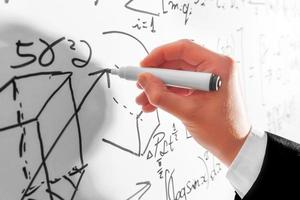 Man writing complex math formulas on whiteboard. Mathematics and science photo