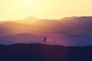 Woman standing on the hill, practicing yoga. photo