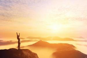 Happy man with hands up on the top of the world above clouds. Bright future photo