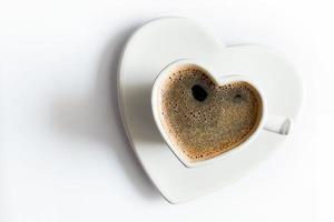 taza en forma de corazón de café negro sobre blanco. amar foto