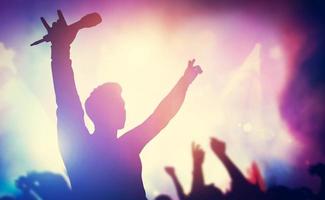 Excited singer raising hands on stage. photo