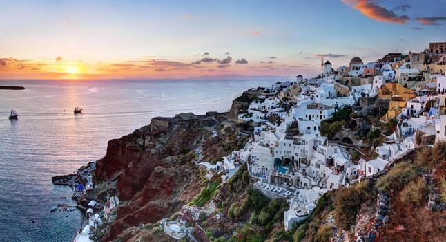 ciudad de oia en la isla de santorini, grecia al atardecer. panorama de los famosos molinos de viento foto