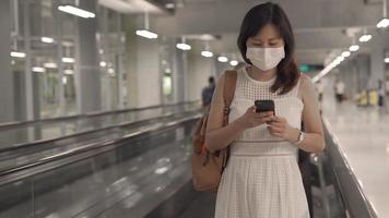 una giovane donna asiatica che indossa una maschera all'aeroporto sta per raggiungere l'aereo al gate. viaggiare durante l'epidemia di covit-19