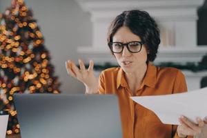 Stressed Italian businesswoman feels angry with error or mistake while remotely working on Christmas photo