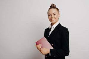 mujer de negocios femenina con cuaderno sonriendo alegremente a la cámara foto