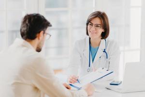 Young female doctor consults patient, shows information and prescription in clipboard, talk about medical checkup, pose at clinic, explains health insurance contract, read service agreement. photo