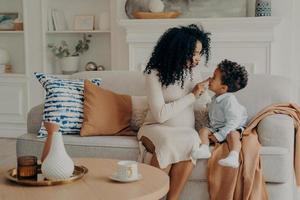 retrato de una hermosa familia embarazada, madre e hijo, raza étnica afro sentada en un sofá foto