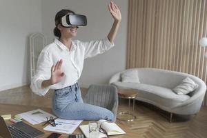 Businesswoman in VR headset on head touching 3d objects while working in modern office photo
