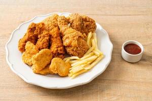 pollo frito con papas fritas y nuggets en un plato foto