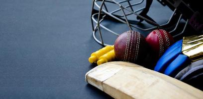 Old training cricket sport equipments on dark floor, leather ball, wickets, helmet and wooden bat, soft and selective focus, traditional cricket sport lovers around the world concept. photo