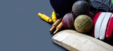 Old training cricket sport equipments on dark floor, leather ball, wickets, helmet and wooden bat, soft and selective focus, traditional cricket sport lovers around the world concept. photo