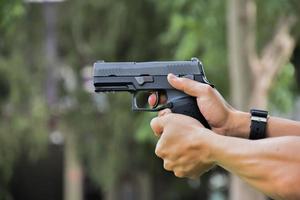 Pistola automática de 9 mm sujeta en la mano derecha del tirador, concepto de seguridad, robo, gángster, guardaespaldas en todo el mundo. enfoque selectivo en pistola. foto