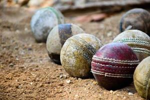 viejas pelotas de cricket de cuero para entrenar y practicar en el suelo de arena al lado de la cancha, enfoque suave y selectivo en la pelota de cricket roja. foto