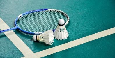 Badminton sport equipments on green floor shuttlecocks, rackets, shoes, selective focus on shuttlecocks, badminton sport playing lover concept. photo