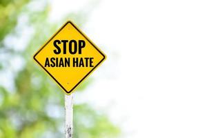 Yellow label traffic sign STOP ASIAN HATE on cement pole beside the rural road with blurred background, copy space, concept for calling drivers to stop Asian people who lived around the world. photo